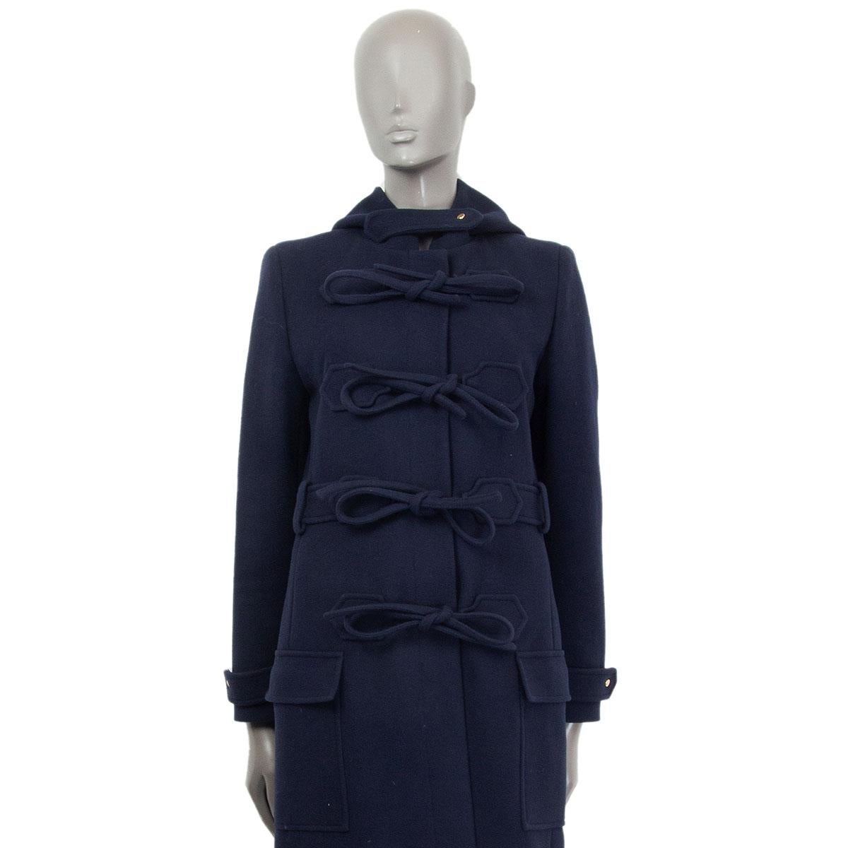 authentic Balenciaga hooded coat in blue virgin wool (75%) and polyamide (25%) with one epaulette at the neck and at the sleeves hem. Closes with concealed buttons and binding ribbons on the front with flap pockets. Lined in black cupro (100%). Has