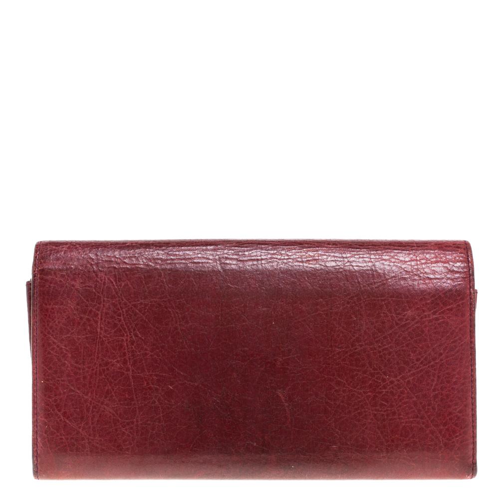 Dieses Portemonnaie aus dem luxuriösen Modehaus Balenciaga kann allein oder in der Handtasche getragen werden. Er ist aus bordeauxfarbenem Leder gefertigt, das ihm einen raffinierten Look verleiht. Sie verfügt über die charakteristischen Nieten- und