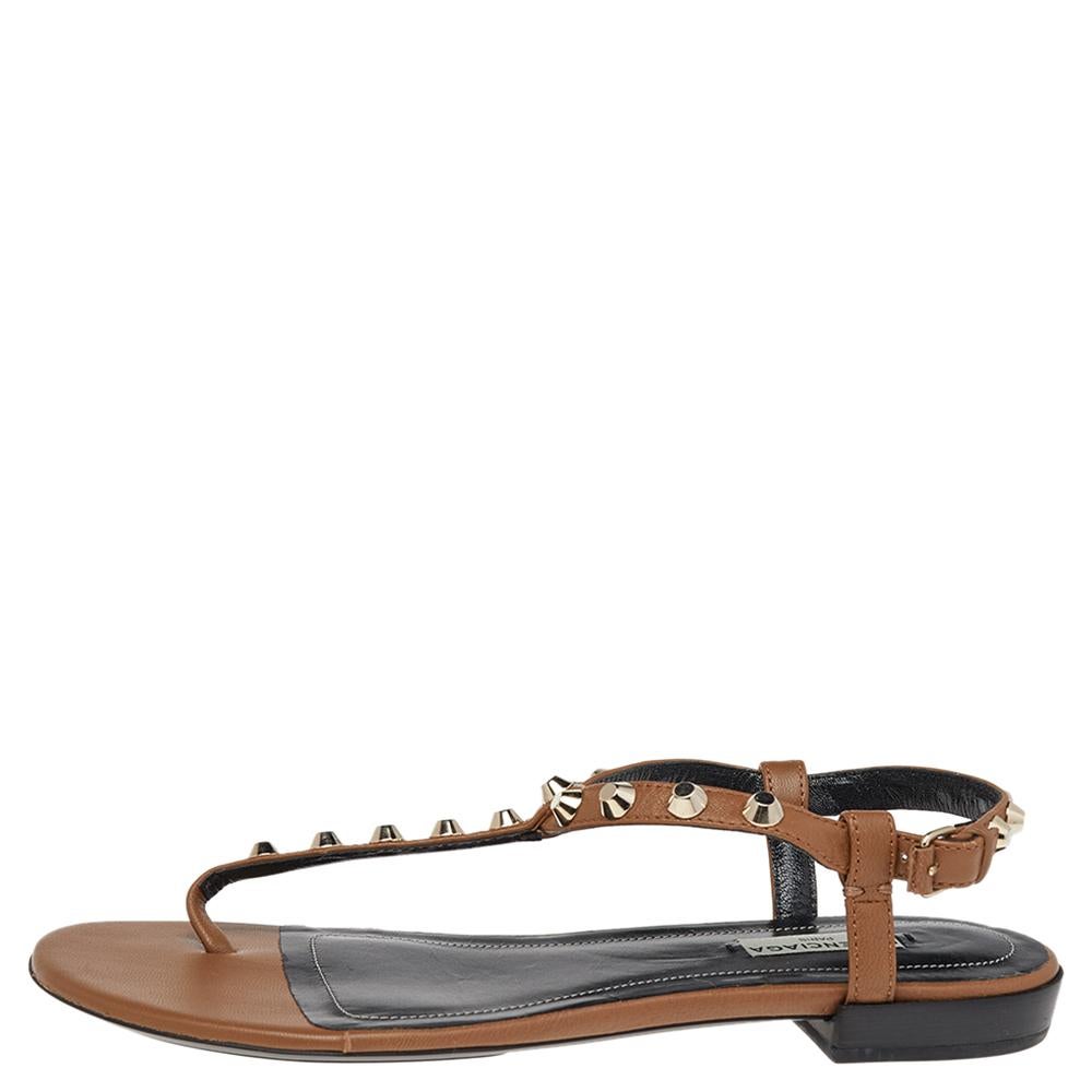 How lovely do these Arena sandals from Balenciaga look! These brown sandals are crafted from leather and feature an open-toe silhouette. They flaunt a thong design with multiple studs adorning the straps. Equipped with buckled ankle straps and