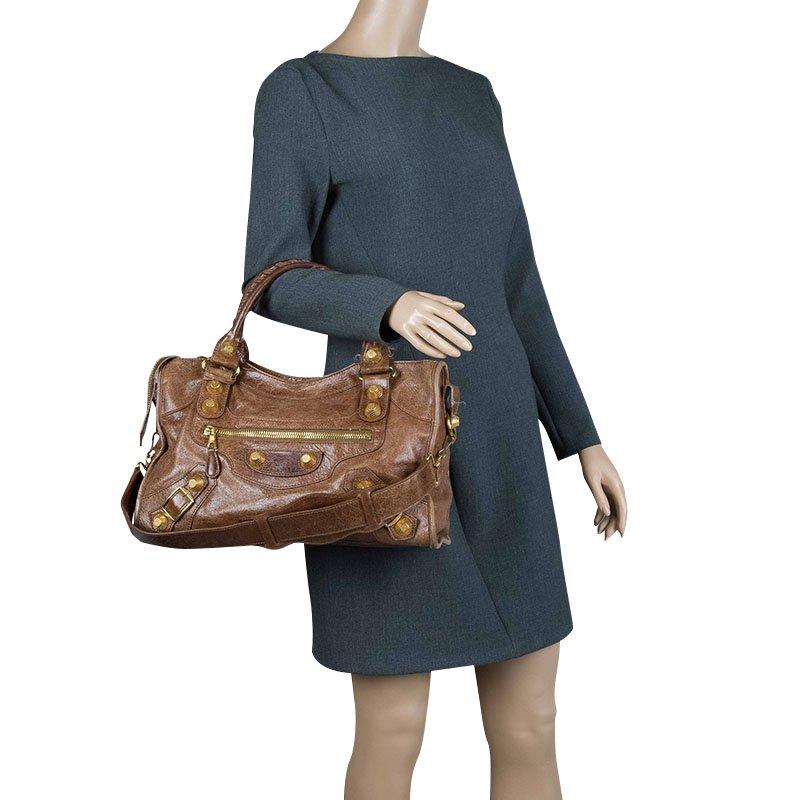 Crafted from luxurious brown leather, this Balenciaga bag is an easy match with most outfits. Its distinctive feature is the bold gold studs and has rolled, top handles. The front zipped pocket in gold-tone hardware, framed leather mirror and a