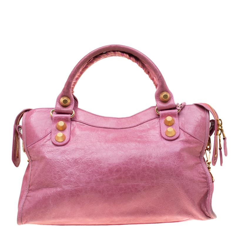 This GH City bag from Balenciaga is perfect for all your outings. The pink leather bag is unique in its silhouette and features an interplay of large studs and buckles. With a creative edge, the bag has a front zip pocket, round leather handles, and