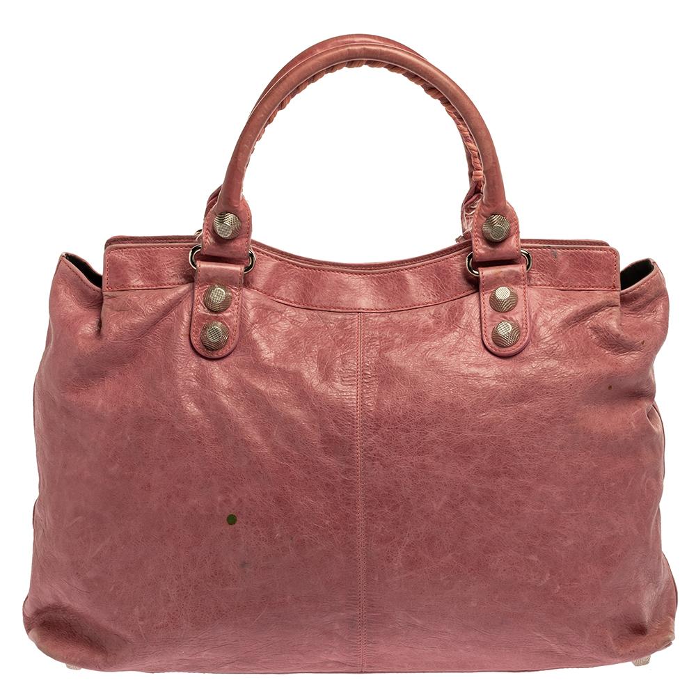 This in-vogue tote by Balenciaga will give a classy effect to your outfit. Crafted from fine leather in the bubble gum pink shade, this SGH Brief creation features two rolled handles. The bag is adorned with silver-tone studs, buckle motifs and is