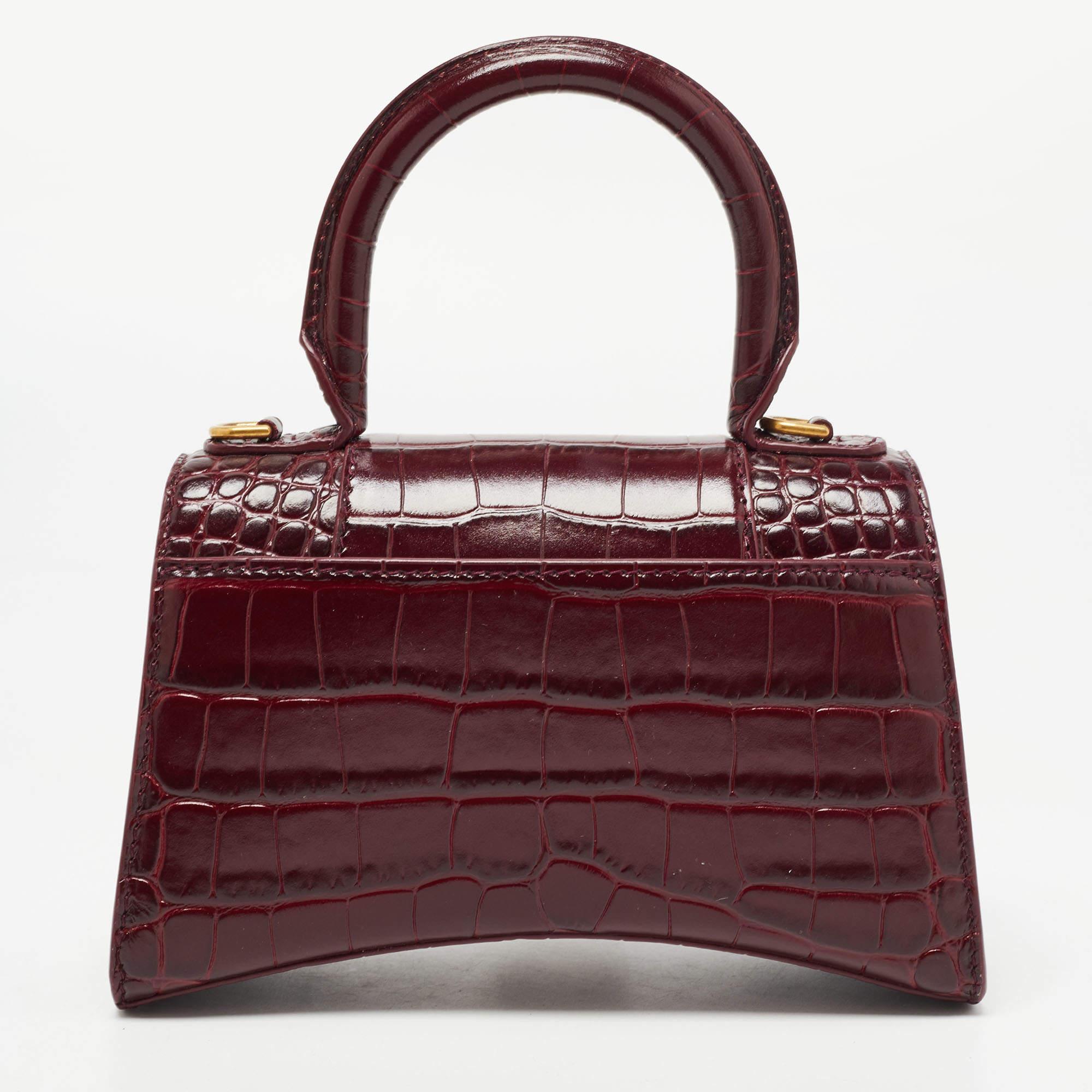 Balenciaga's Hourglass is inspired by the silhouettes of its sculptural blazers of the 1950s and, with its very distinctive shape, knows how to start a conversation. The curved bottom of this croc-embossed leather construction is beautifully