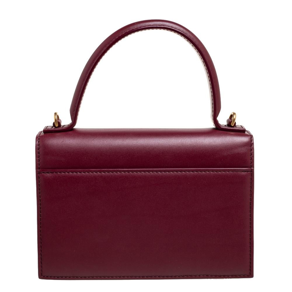 Balenciaga brings to your closet this exquisite top handle bag that is perfect for evening events. Crafted from leather, this burgundy bag has a stylish shape and is finished with gold-tone hardware and a well-sized interior for your essentials.