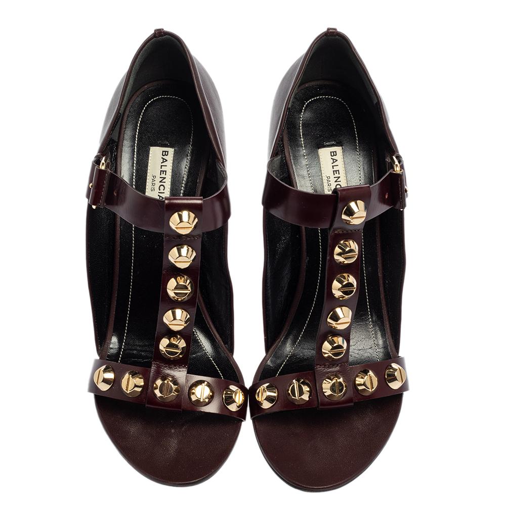 These Balenciaga wedge sandals are the ideal accessory to dress any outfit up. Crafted from leather, these burgundy sandals feature an open-toe silhouette. They flaunt a cage design with gold-tone studs adorning the straps. Equipped with buckled