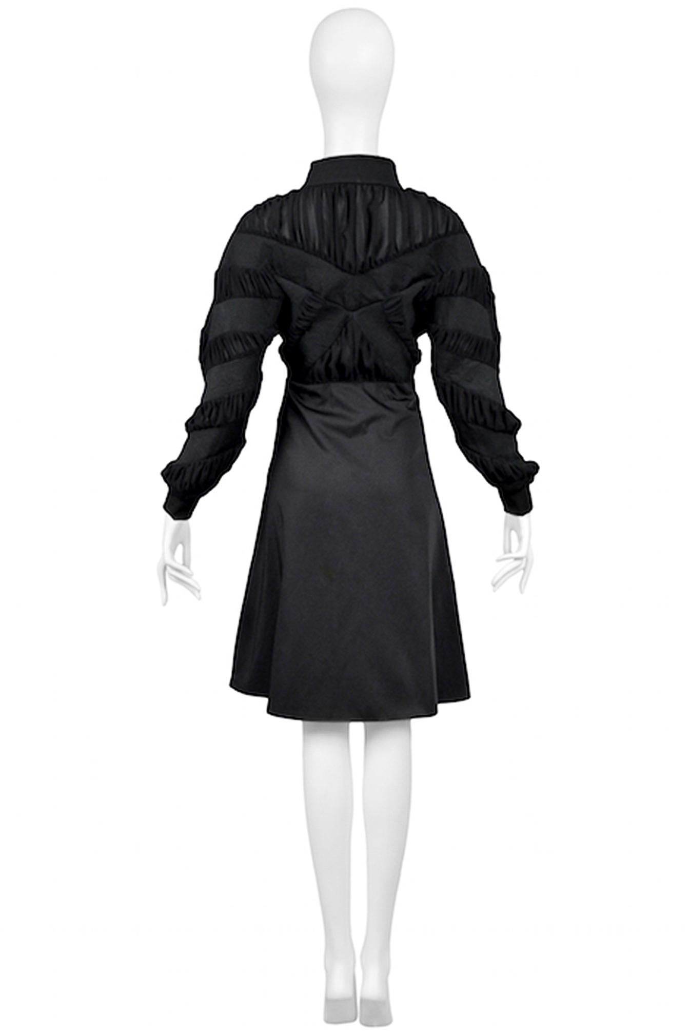 Resurrection Vintage is excited to offer a vintage Balenciaga by Nicolas Ghesquière black coat dress featuring a high collar, ruffle insets in the bodice and sleeves, a fitted waist, peplum, long sleeves with cuffs, circle skirt, and silver center