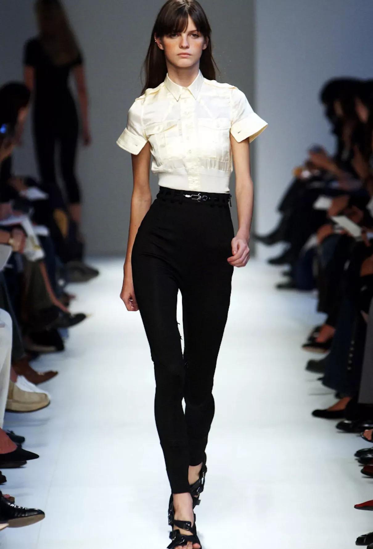 A coveted piece from Nicolas Ghesquière’s visionary Spring/Summer 2003 collection for Balenciaga, this cropped scuba top epitomizes the designer’s early 2000s mastery of form, fabrication, and futuristic tailoring.
Crafted from luminous beige satin