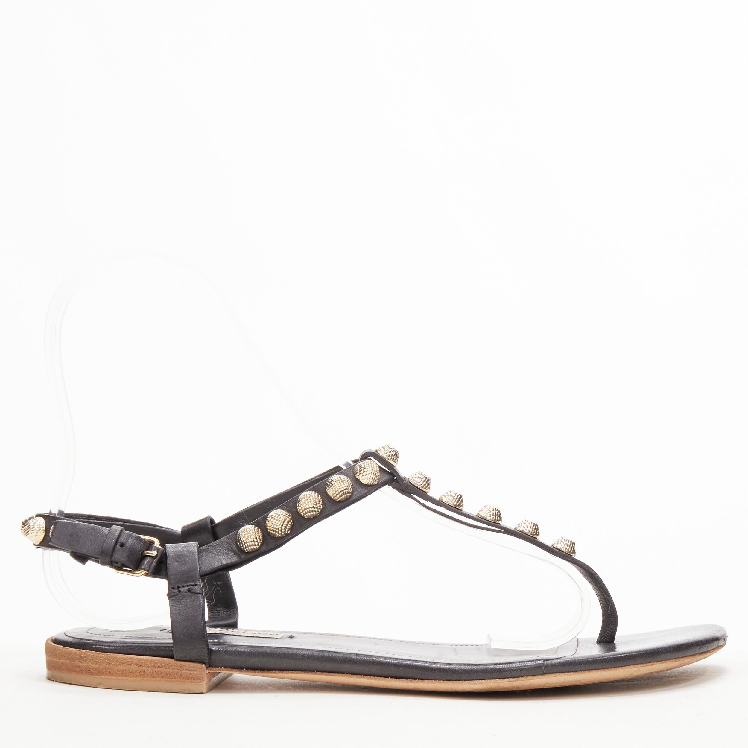 BALENCIAGA Cagole black leather gold textured  stud T-strap flat sandals EU38
Brand: Balenciaga
Material: Calfskin Leather
Color: Black
Pattern: Solid
Closure: Ankle Strap
Extra Detail: Textured gold-tone hardware. Stacked wooden heel.
Made in: