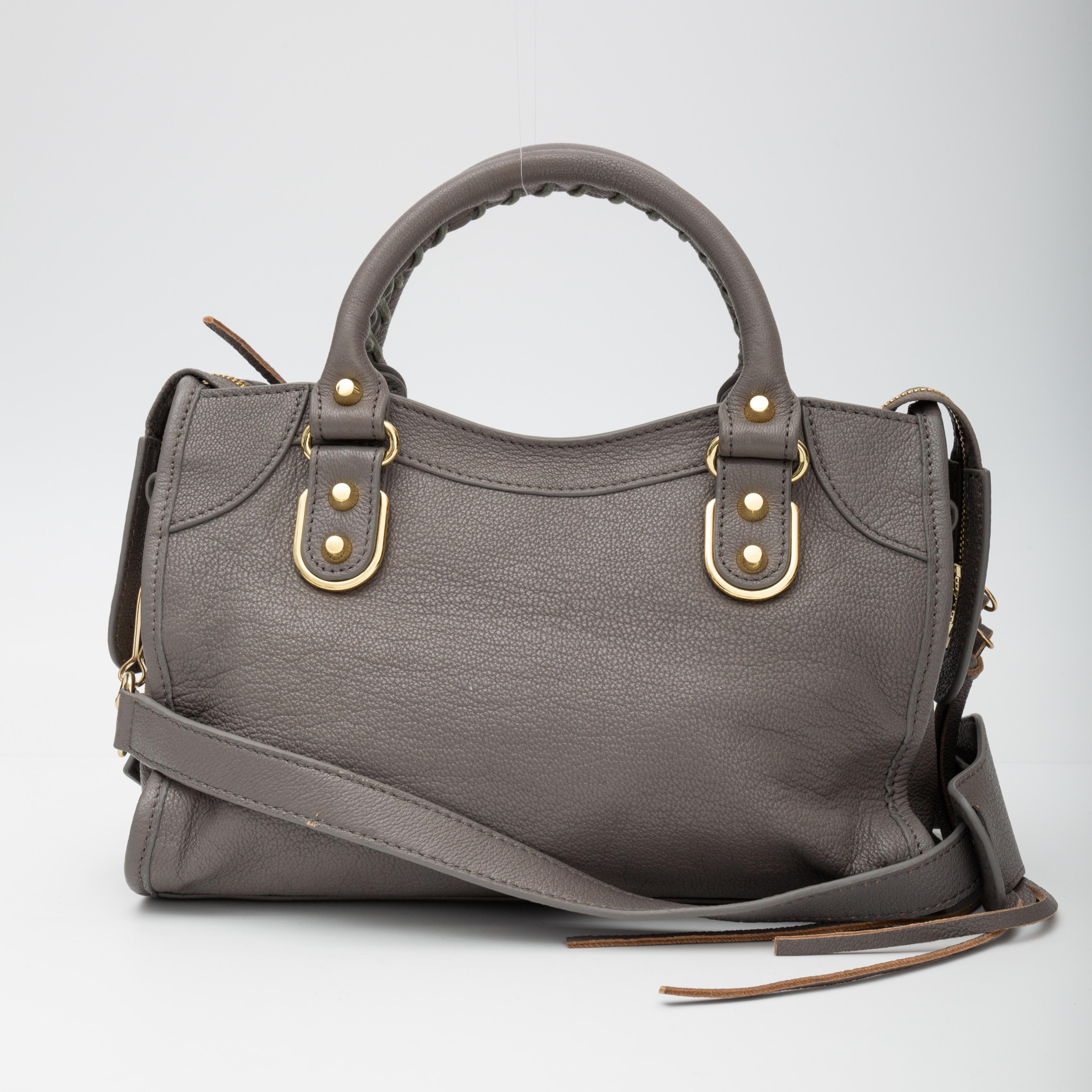 This stylish tote is made of richly textured chèvre goatskin leather in grey. The bag features hand-stitched rolled leather top handles, an optional cross-body shoulder strap, an exterior zipper pocket for the hanging mirror, and gold hardware. The