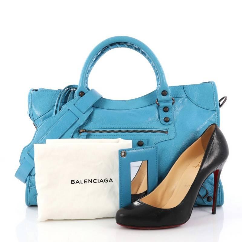This authentic Balenciaga City Classic Studs Handbag Leather Medium is for the on-the-go fashionista. Constructed in light blue leather, this popular bag features dual braided woven handle straps, front zip pocket, iconic classic studs and buckle