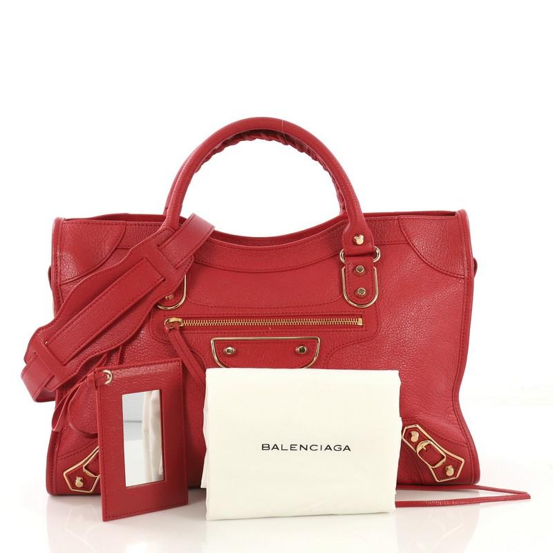 This Balenciaga City Classic Studs Metallic Edge Bag Leather Medium, crafted from red leather, features dual braided woven handles, studs and buckle details, front zip pocket, and gold-tone hardware. Its top zip closure opens to a black fabric