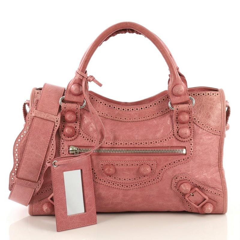 This Balenciaga City Giant Brogues Bag Leather Medium, crafted in pink leather, features braided woven handles, leather perforated trim, front zip pocket, and matte silver-tone hardware. Its top zip closure opens to a black fabric interior with side