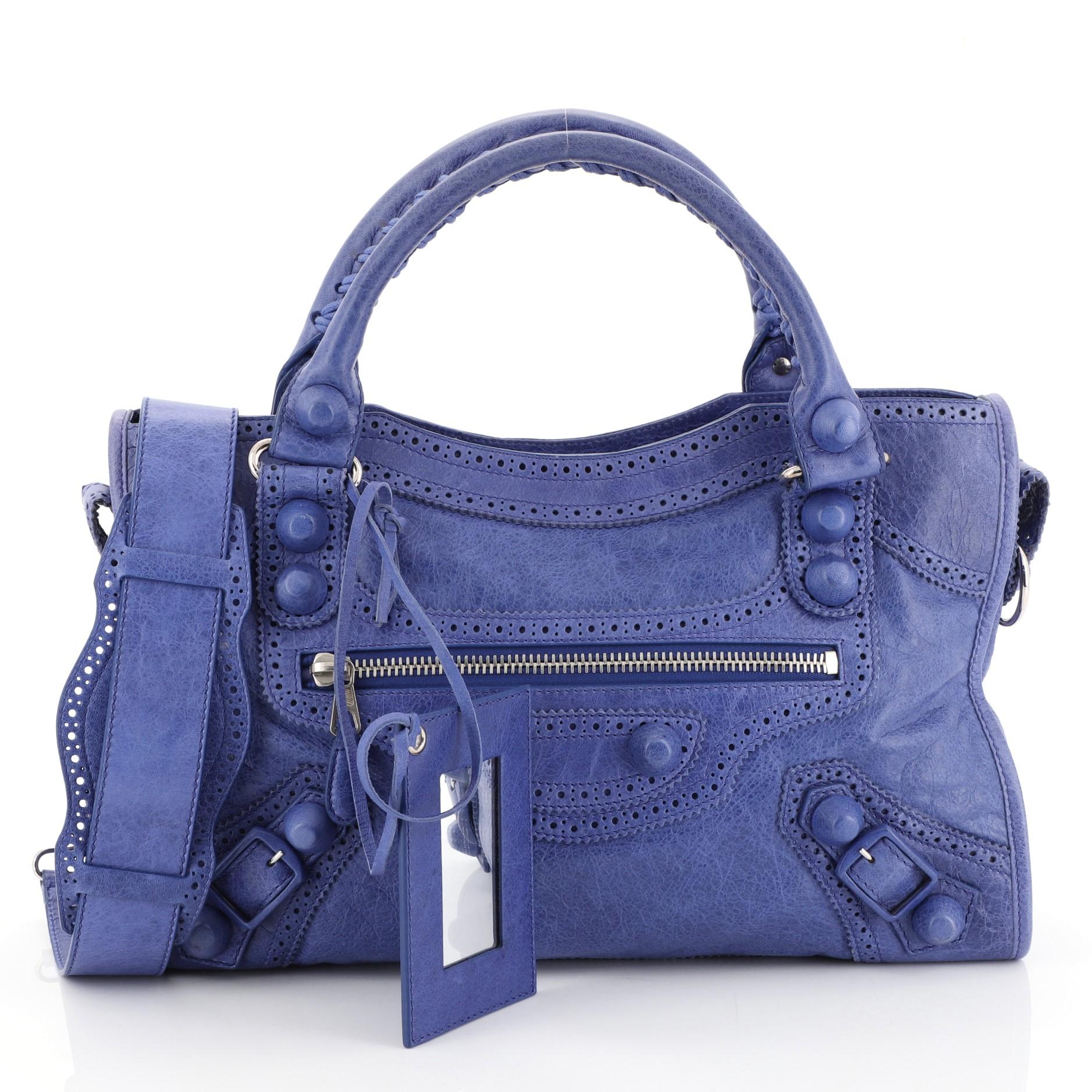 This Balenciaga City Giant Brogues Bag Leather Medium, crafted in blue leather, features braided woven handles, leather perforated trim, front zip pocket, and silver-tone hardware. Its top zip closure opens to a black fabric interior with side zip