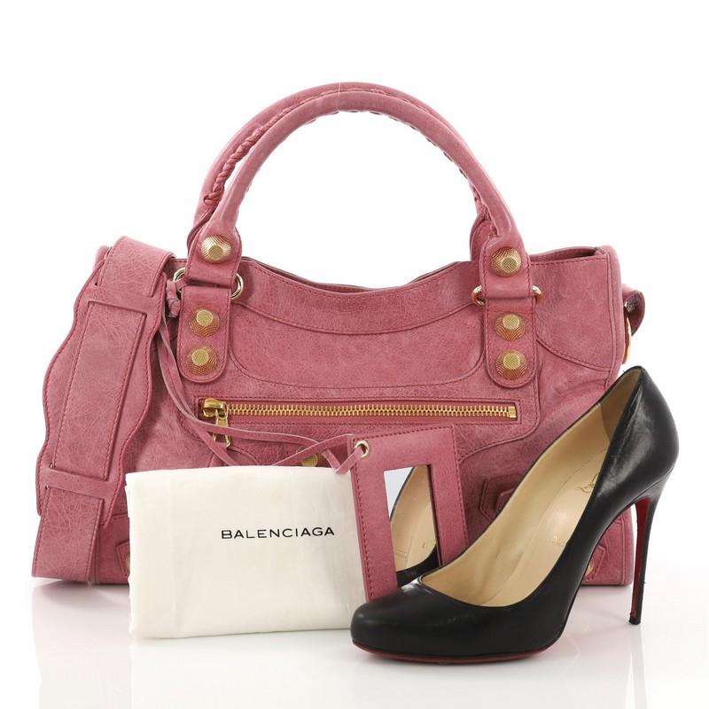 This Balenciaga City Giant Studs Handbag Leather Medium, crafted from pink leather, features dual braided woven handles, exterior front zip pocket, and gold-tone hardware. Its top zip closure opens to a black fabric interior with side zip and slip