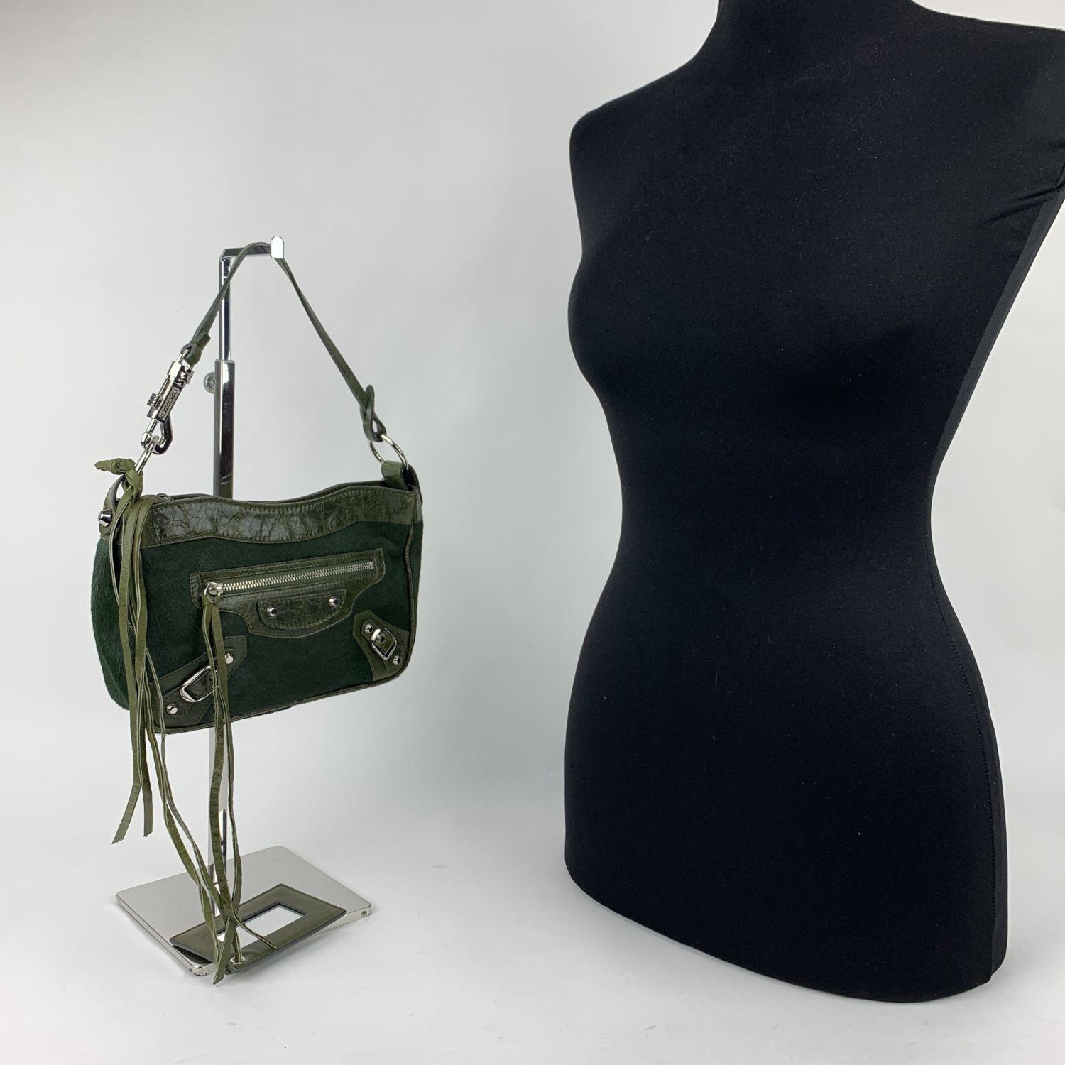 Balenciaga Motocross mini bag bag, crafted from dark green pony hair with leather trim and handle. Buckle detailing on bottom corners and decorative silver metal studs. Top zip closure. Front zip-fastening pocket. Black canvas lining with 1 side zip