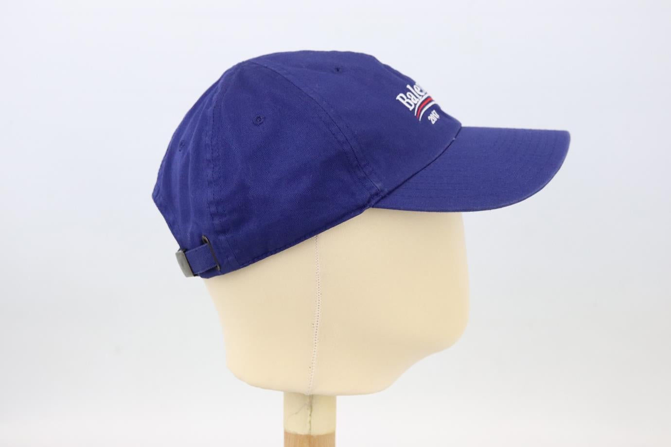 Balenciaga embroidered cotton twill baseball cap. Made from blue cotton-twill with white and red logo-embroidery on the front. Blue. Buckle fastening at back. 100% Cotton. Size: Large.  Brim Depth: 3 in. Circumference: 21.4 in.