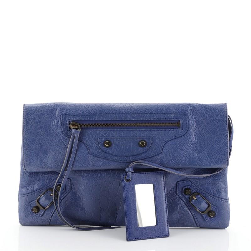 This Balenciaga Envelope Clutch Classic Studs Leather, crafted in blue leather, features a front zip pocket, classic studs and buckle details and bronze-tone hardware. Its magnetic snap closure opens to black fabric interior. 

Estimated Retail