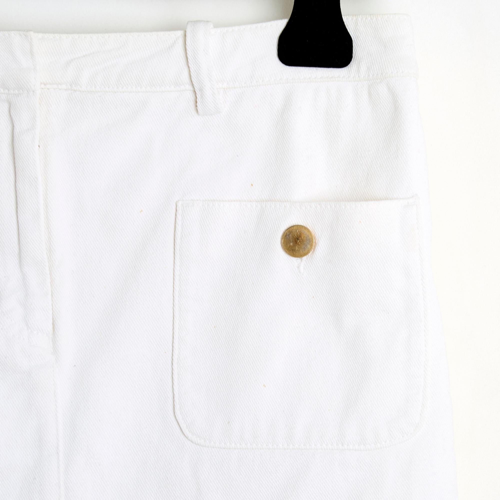 Balenciaga mini skirt by Nicolas Ghesquière in white cotton twill (denim), 2 patch and buttoned pockets on the front, belt loops, zip and hidden hook closure, white cotton canvas lining. Size 36FR: waist (low) 38 cm, length 30 cm. The skirt is in