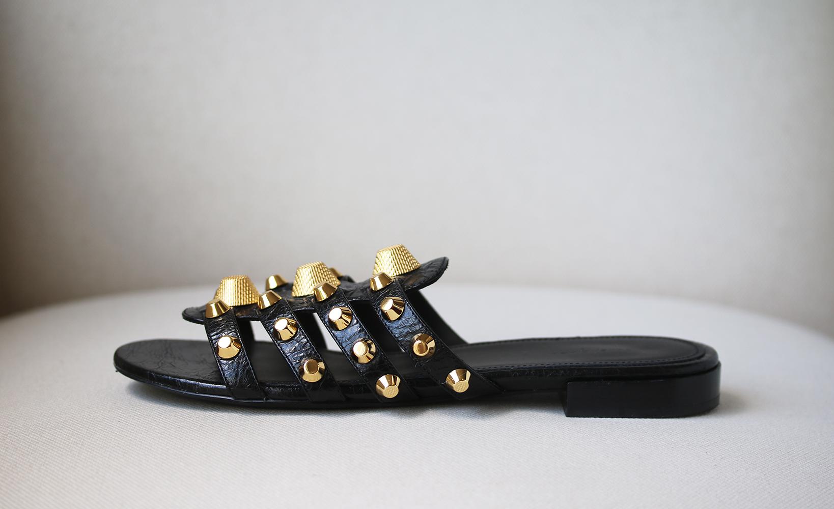 Balenciaga's 'Giant' slides are embellished with the same signature thimble-inspired studs as the brand's 'City' tote. This gladiator style is made from glossy textured-leather and has a caged vamp that elegantly frames your foot. Slight heel. Black