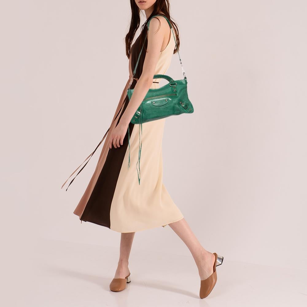 This Balenciaga Classic First shoulder bag is perfect for everyday use. Crafted from green leather, the bag has a feminine silhouette with dual top handles, a removable shoulder strap, and silver-tone hardware. The zip-top closure opens to a
