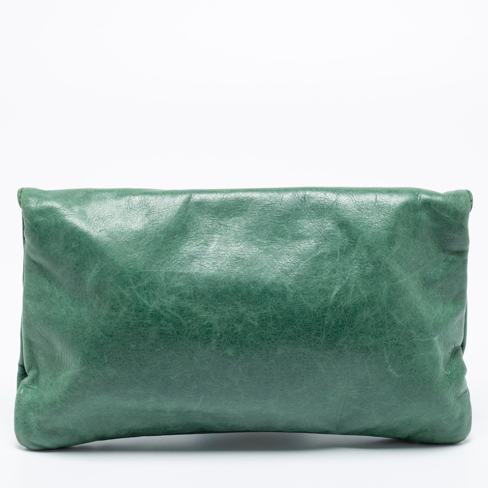 This Balenciaga GGH clutch is perfect to carry for days when you need only your essentials. Punctuated with the label's signature studs, this envelope-style clutch features a zippered pocket on the flap and flaunts a green hue. It is complete with a