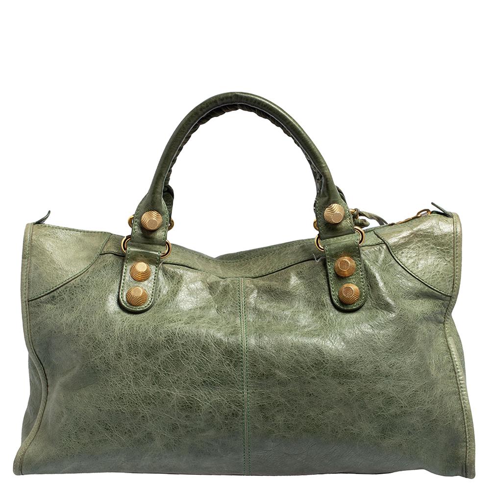 This Balenciaga Work bag is perfect for everyday use. Crafted from leather in a gorgeous green hue, the bag has a feminine silhouette with two top handles and gold-tone hardware. The zipper closure opens to a fabric-lined interior and the bag is