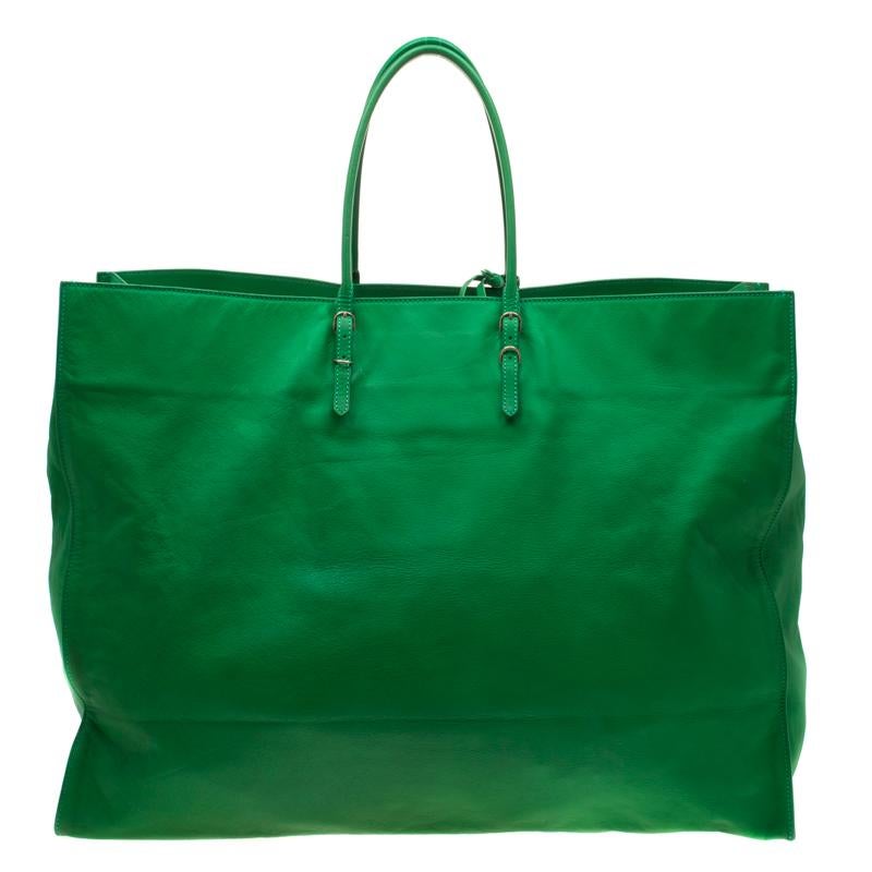 Defined by its grand size, this Papier A3 from Balenciaga is a bag meant to assist you on busy days. It is crafted from green leather with gold-tone studs, two rolled handles, an exterior zip pocket and matching detachable mirror. The suede interior