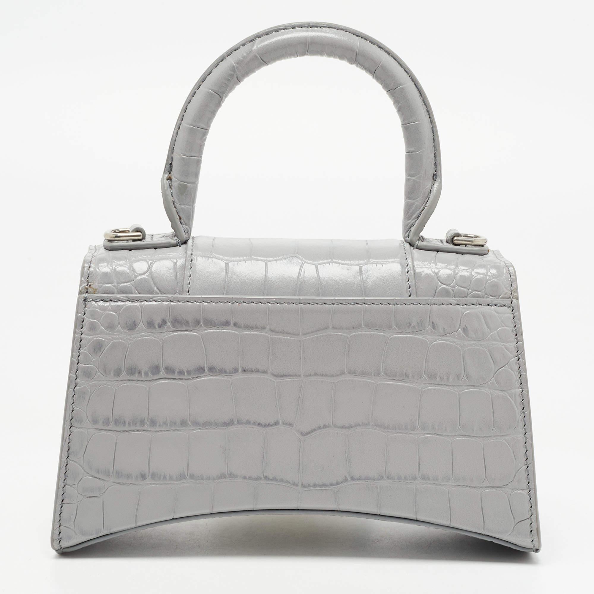 Balenciaga's Hourglass is inspired by the silhouettes of its sculptural blazers of the 1950s and, with its very distinctive shape, knows how to start a conversation. The curved bottom of this croc-embossed leather construction is beautifully