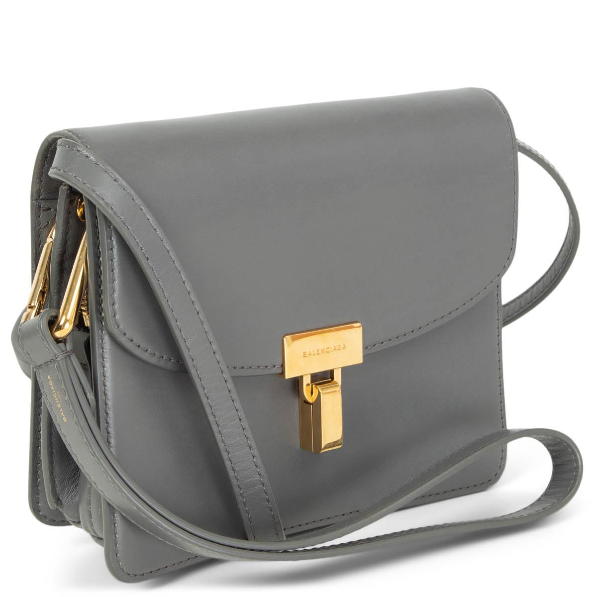 100% authentic Balenciaga Lock Shoulder Bag in grey smooth calfskin featuring gold-tone hardware. Opens with a curved front flap and turn-lock to a leather lined interior that is divided in 2 compartments one of them with a zipper closure and 2 flat
