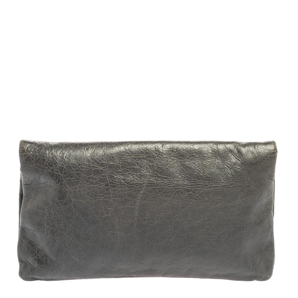 This Balenciaga clutch is a stylish creation that's sure to complement a variety of looks. This flap-style clutch is crafted from leather and accented with signature metal studs, corner buckle detailing, and a front zip pocket. The interior is lined
