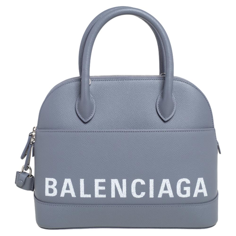 Diese Balenciaga S Ville Tasche ist sehr trendy und extrem stilvoll. Sie müssen sie unbedingt haben! Die graue Kreation ist aus Leder gefertigt und mit dem Markenlogo auf der Vorder- und Rückseite versehen. Sie hat zwei Griffe an der Oberseite und