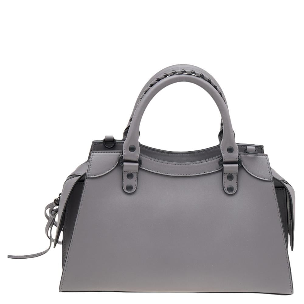 One of the most exemplary and memorable creations of the House is this spectacular Neo Classic tote from Balenciaga. It has been designed using grey leather and showcases dual top handles, black-toned hardware, and a shoulder strap. It accommodates