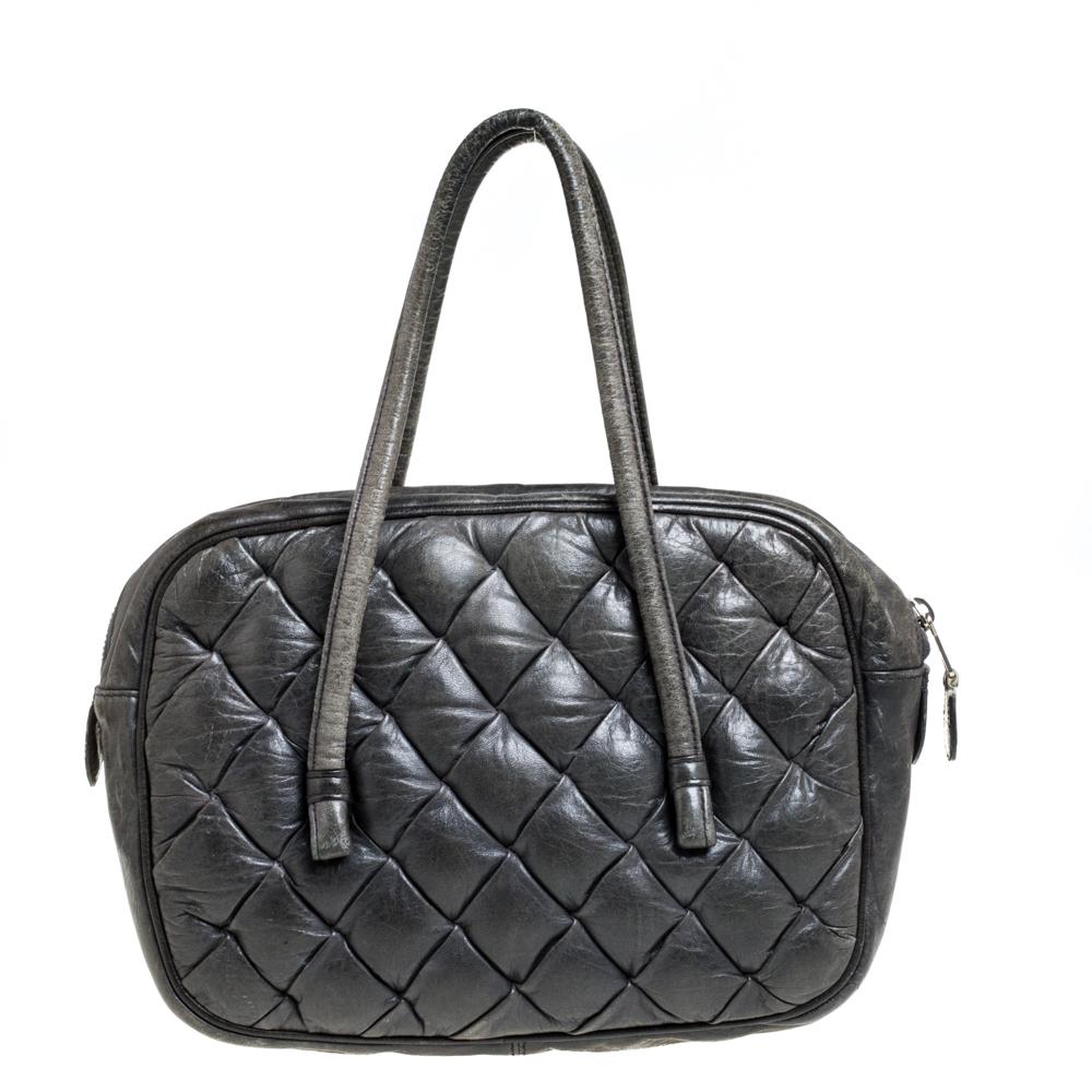 This strikingly stylish bag does dual work as a fashion accessory and practical necessity. Crafted from grey leather, it features a quilted pattern and has a structured silhouette. It comes equipped with a zip closure that reveals a fabric-lined