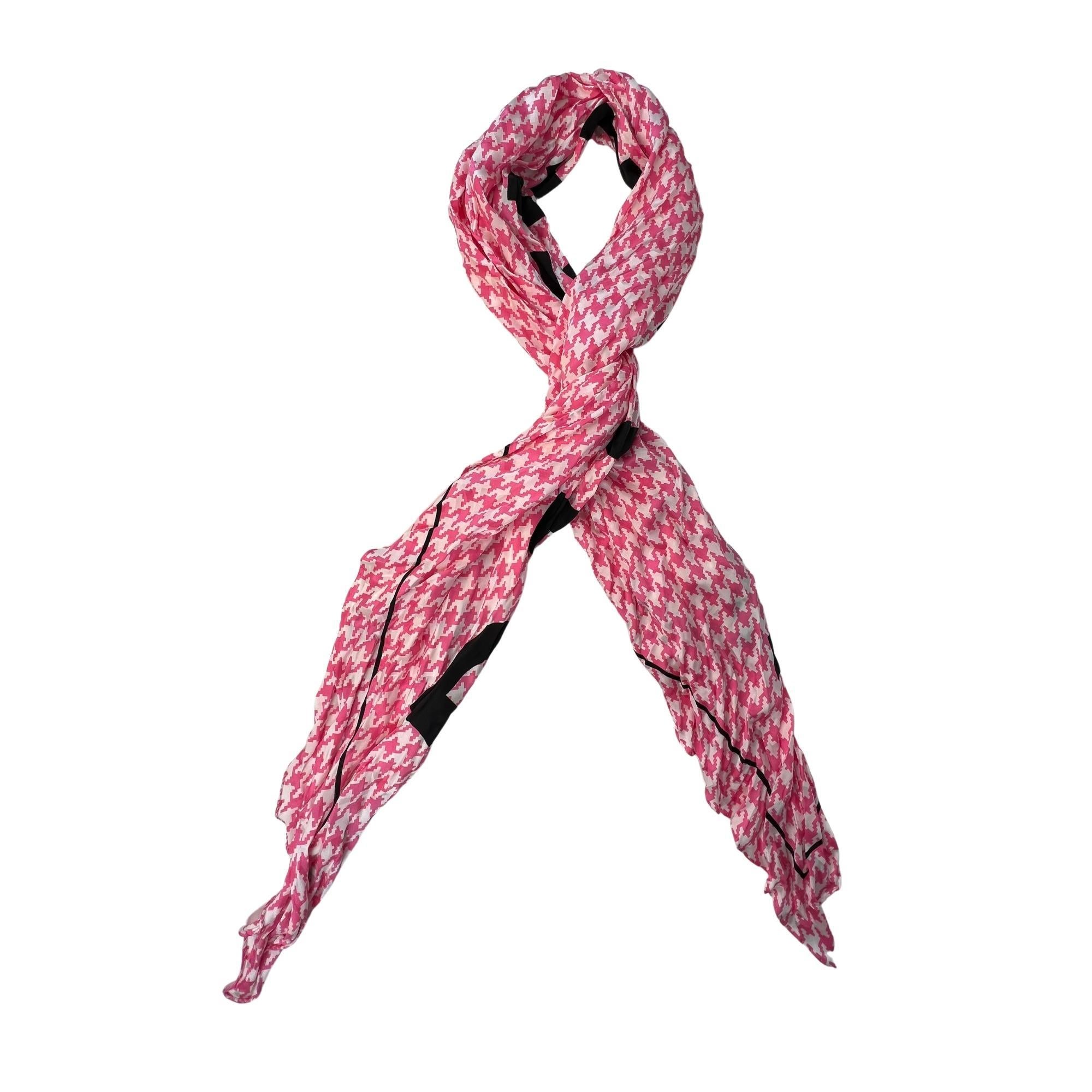 Cette écharpe en soie légèrement froissée présente un imprimé jacquard pied-de-poule rose vif et le logo Balenciaga en lettres noires audacieuses. Nouez-le à votre queue de cheval, à la sangle de votre fourre-tout préféré ou au motif classique du