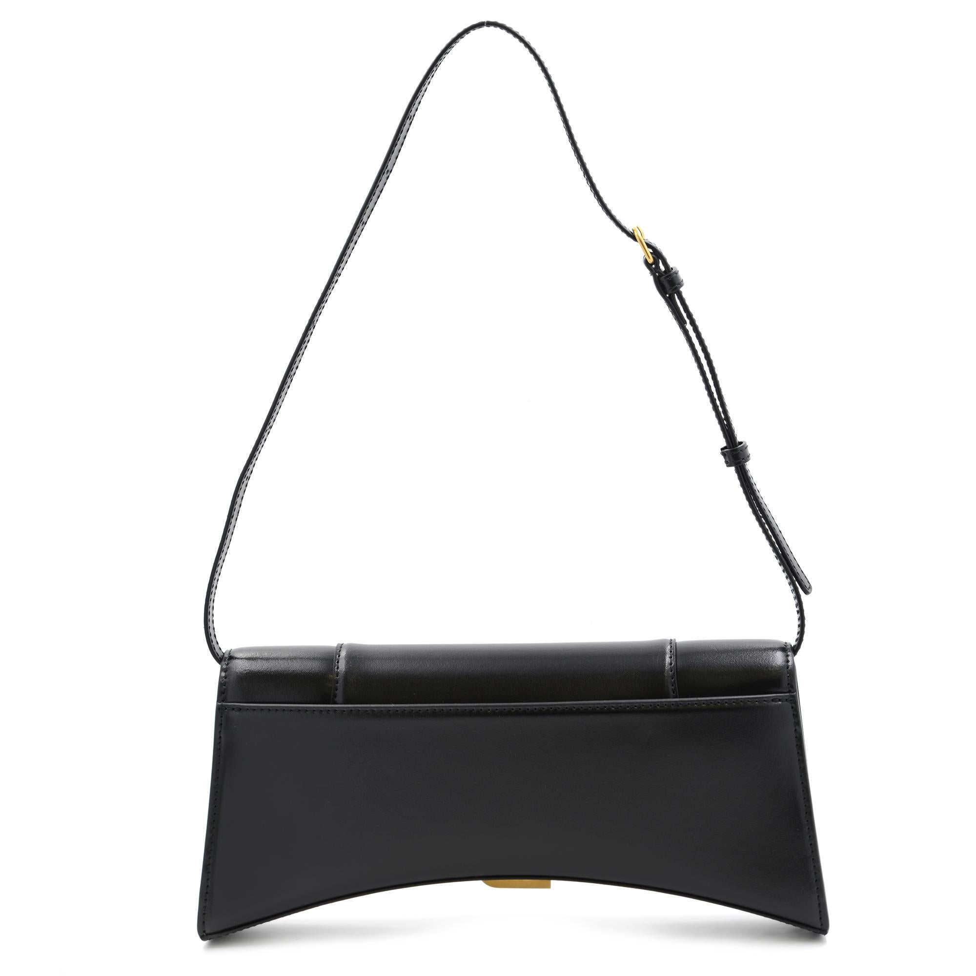 Balenciaga arch Hourglass stretched shoulder bag comes in black leather with a golden-toned metal monogram clasp and a single interior card slot. Black calf leather. Antique gold tone hardware. Snap/Magnetic Closure. Measurements: L 11 inches x W