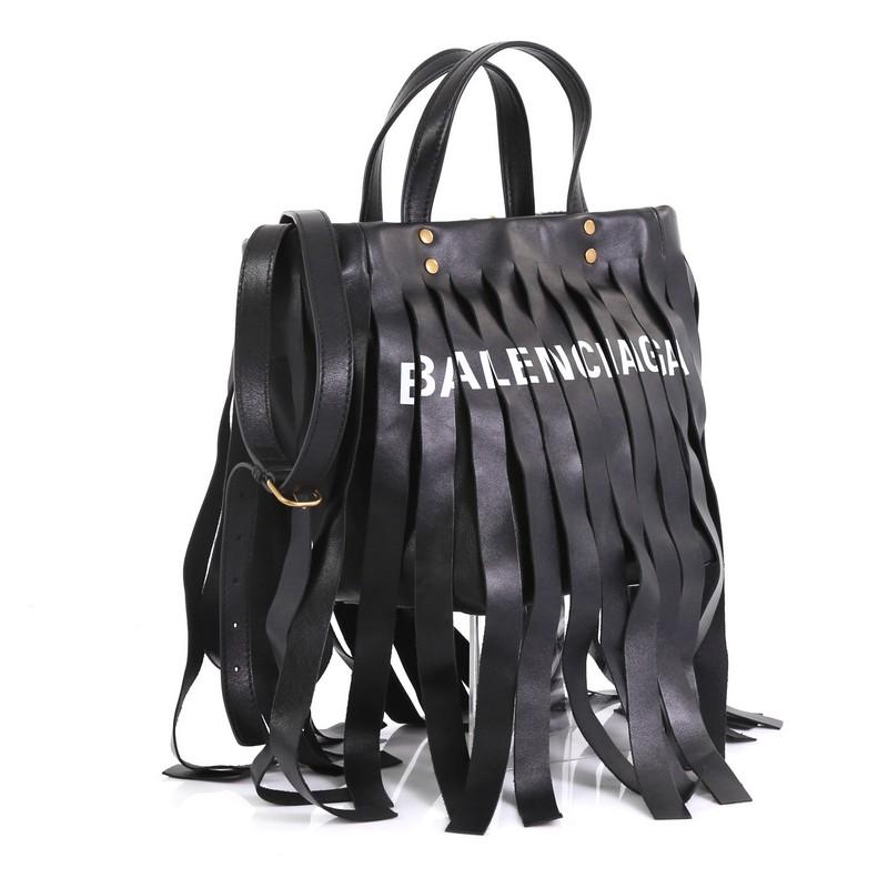 This Balenciaga Laundry Cabas Tote Fringe Leather XS, crafted in black fringe printed leather, features dual stitched top handles and gold-tone hardware. It opens to a black fabric interior with zip and slip pockets. 

Estimated Retail Price: