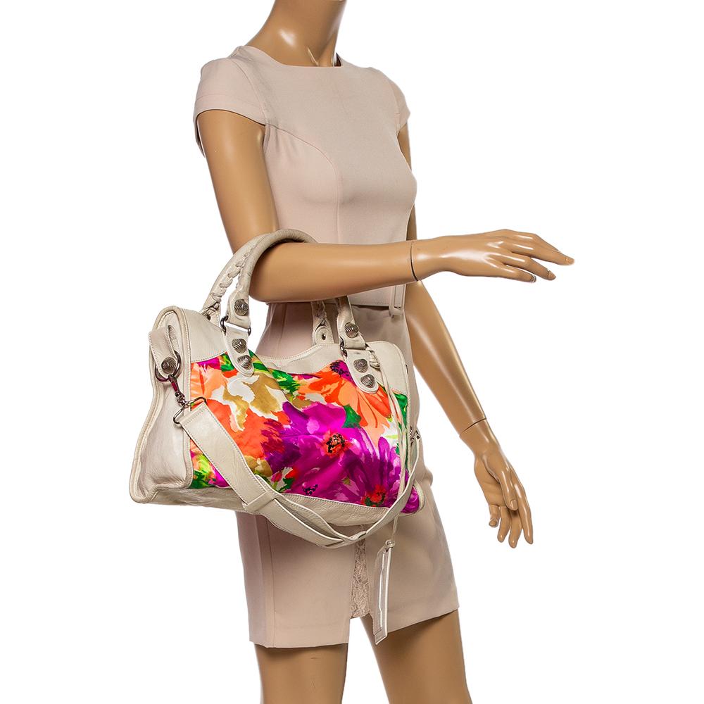 Classy and elegant, this Balenciaga City bag is perfect for the daytime. The bright floral-printed multicolored leather & satin exterior is detailed with large silver-tone studs and buckles, a front zip pocket, double whip-stitched handles, and a