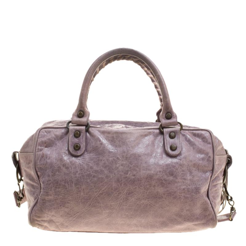 This box bag showcases Balenciaga's relaxed rocker, chic style on a larger scale. This barrel shaped bag is crafted from lilac-colored leather and accented with aged hardware and studs, leather tassels, and a leather framed hand mirror. It is held