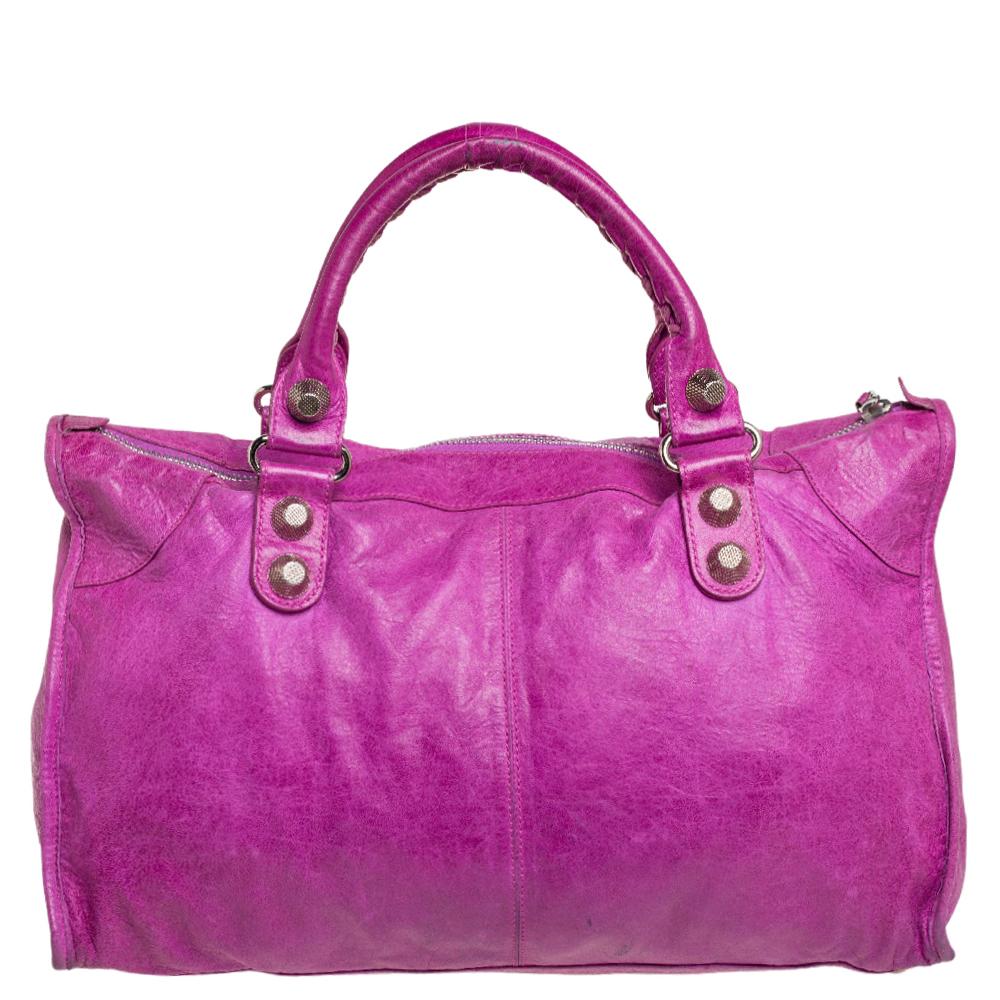 This Balenciaga Work bag is perfect for everyday use. Crafted from leather in a gorgeous hue, the magenta bag has a feminine silhouette with two top handles and silver-tone hardware. The zipper closure opens to a fabric-lined interior and the bag is
