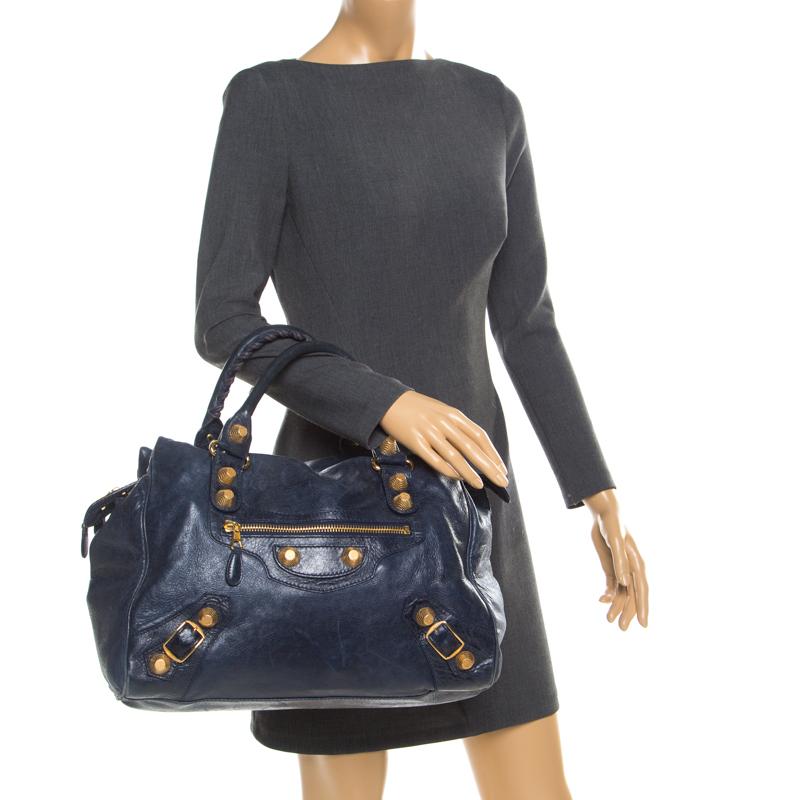 A popular bag among celebrities, this Giant 21 Midday bag by Balenciaga will never leave you unnoticed! It is crafted from marine blue leather and is accented with oversized signature metal buckle and stud details at the front. It comes with a