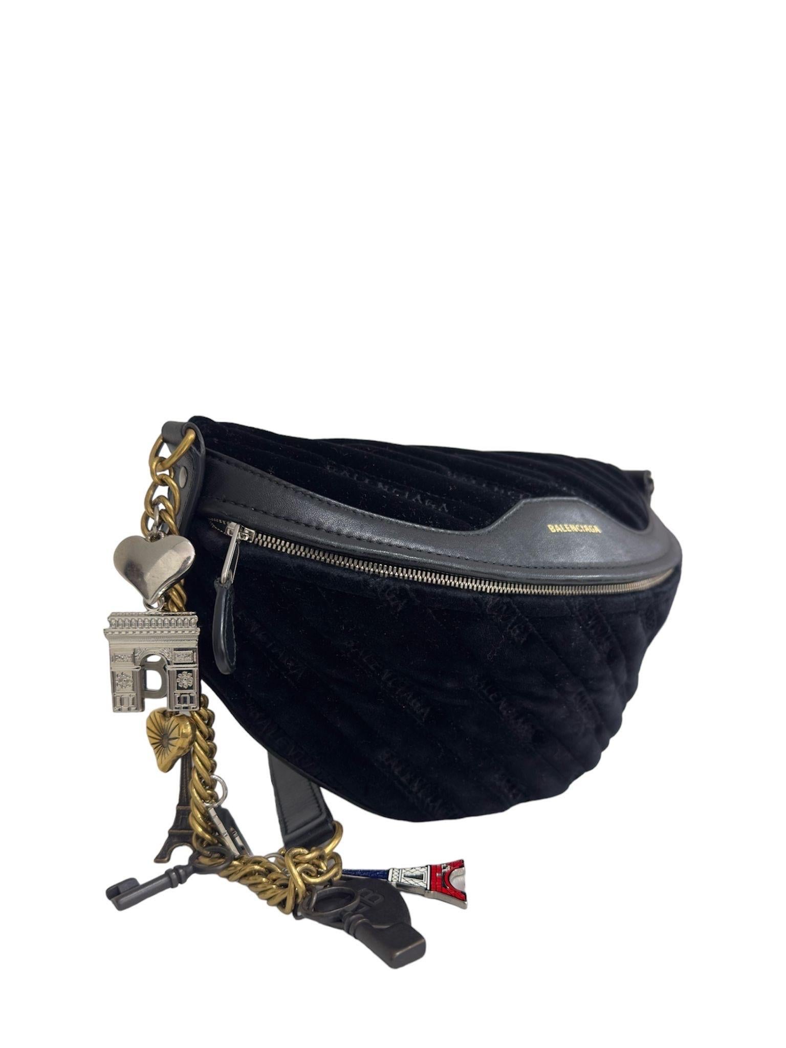 Le sac à main Balenciaga, modèle Souvenir XS, est réalisé en cuir noir avec des insertions en cuir ton sur ton et des ferrures dorées. Il est doté d'une ouverture zippée sur le devant. Munito di una tracolla realizzata in pelle e catena a maglia