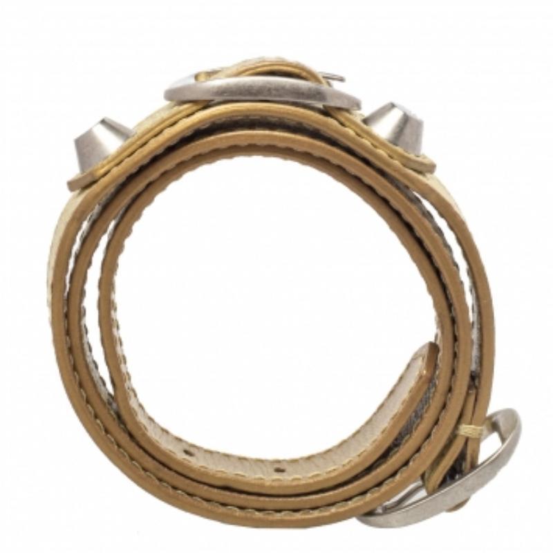 Designed to wrap around your wrist, this Balenciaga bracelet comes from their Arena collection. It has been crafted from metallic gold leather and detailed with buckles and studs in silver-tone metal. This piece deserves a place in your accessory