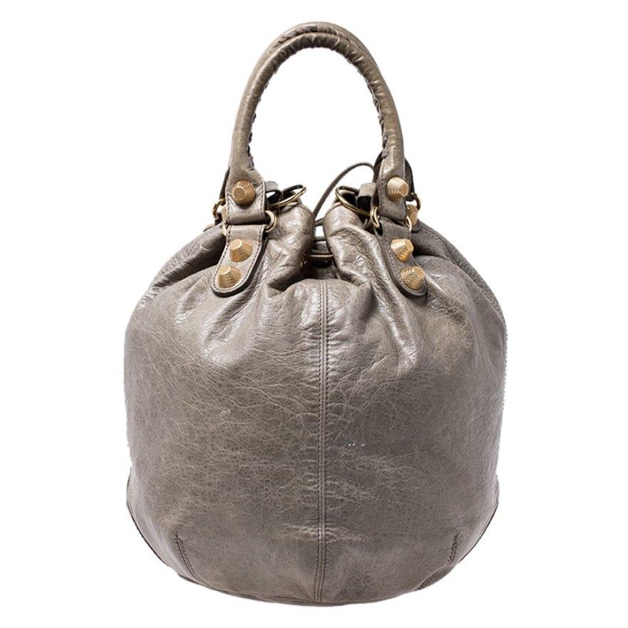 This Balenciaga 'Pompon' hobo bag will become your favorite daytime wardrobe addition! It is crafted from green leather and accented with signature gold-tone metal studs and other hardware details. The exterior is accented with a rolled top handles,