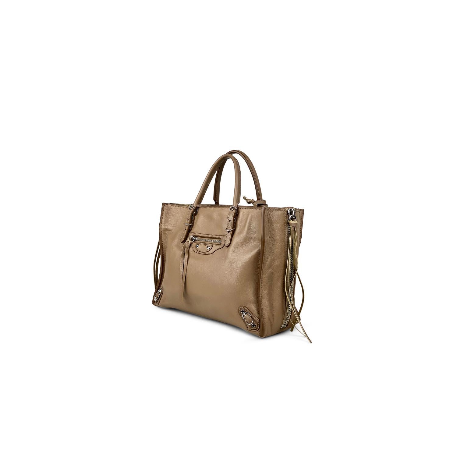 Taupe calfskin leather Balenciaga Mini Papier A6 Zip Around bag with

- Silver-tone hardware
- Dual rolled top handles
- Detachable flat shoulder strap
- Stud embellishments and buckle accents at front face
- Single front exterior zip pocket, zip