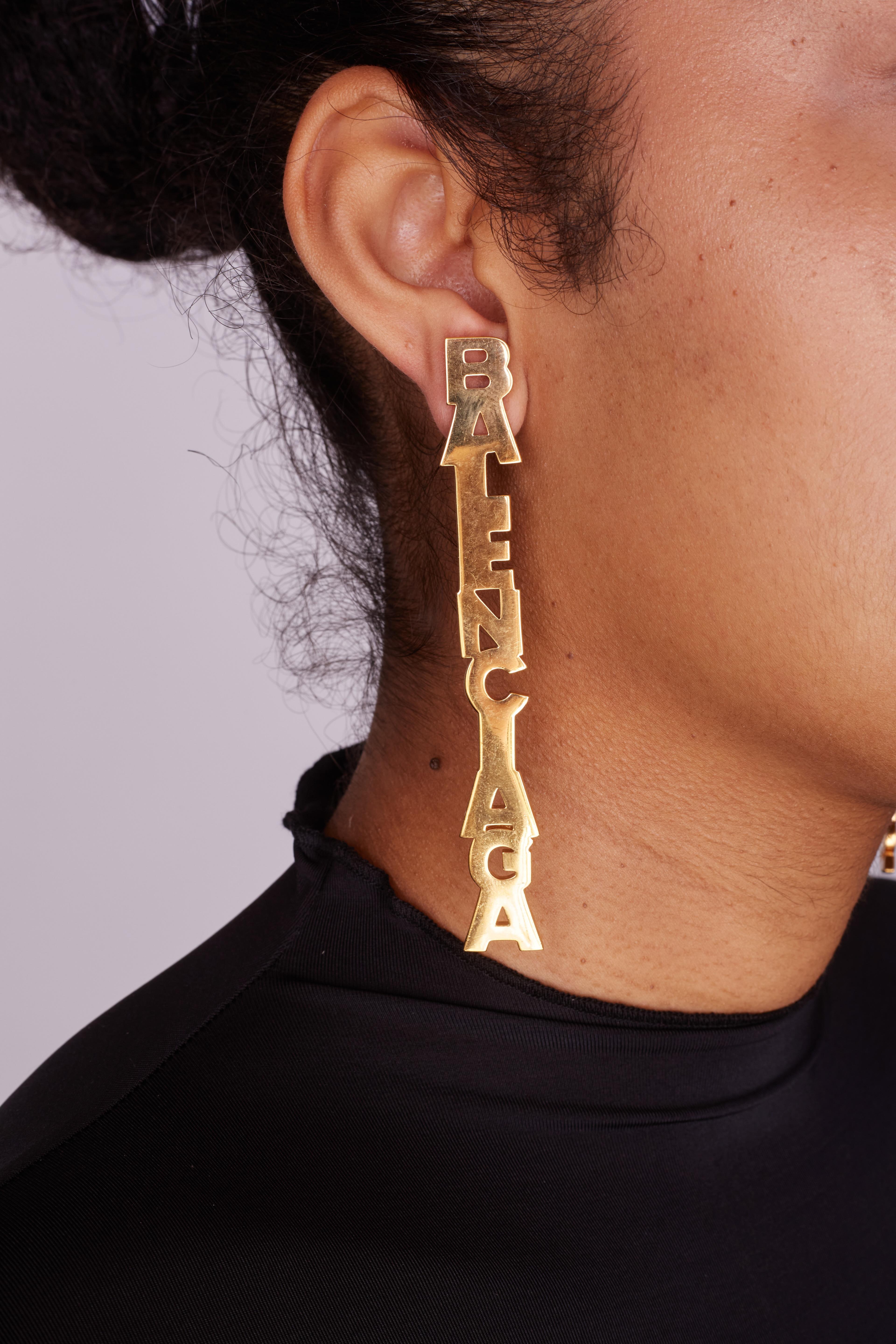 BALENCIAGA MISMATCHED GOLD LOGO I LOVE PARIS DROP EARRINGS

Color: Gold tone
Material: Brass
Marks: Designer Signature
Total Item Weight (g): 36.2
Clasp Style: for pierced ears/Clutch Back

Measures: 4” x .5”
Condition: Good. Pre loved.

Made in