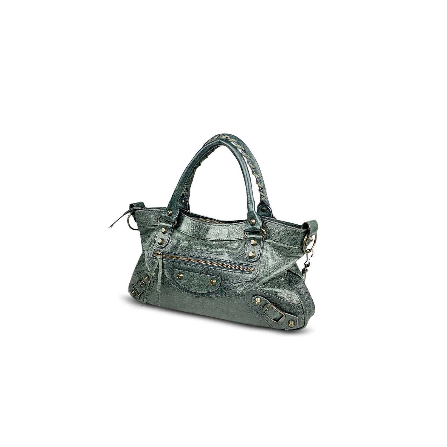 Grey leather Balenciaga Motocross Classic First bag with

- Aged Brass Hardware
- Tonal leather trim
- Dual rolled top handles with whipstitch trim
- Single detachable shoulder strap
- Single zip pocket at front
- Black woven lining, three pockets