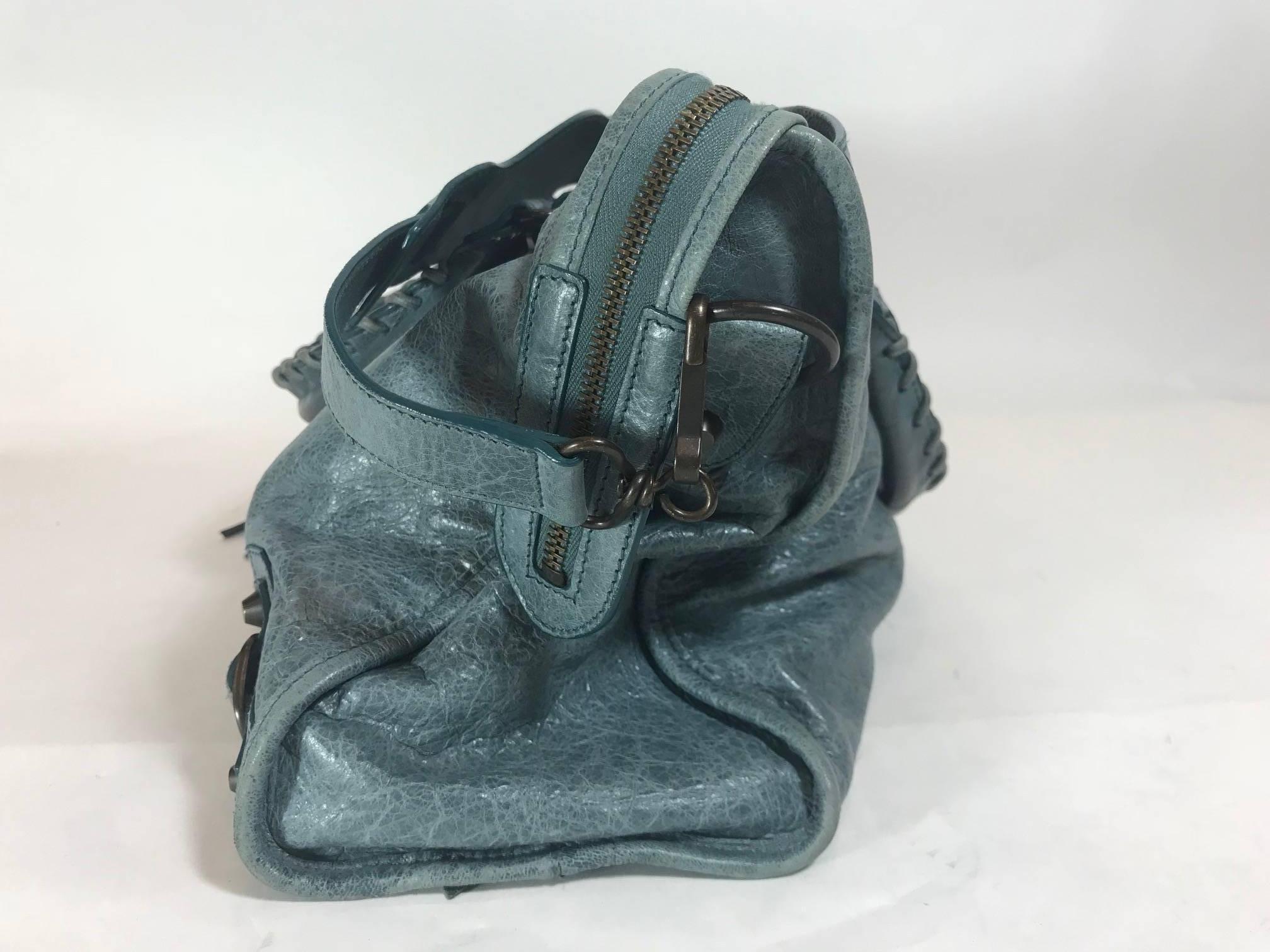 Cerulean leather. Brass hardware. Dual rolled handles featuring whipstitched detail. Detachable flat shoulder strap. Single exterior zip pocket. Stud and buckle embellishments throughout. Black woven lining. Single zip pocket at interior wall and