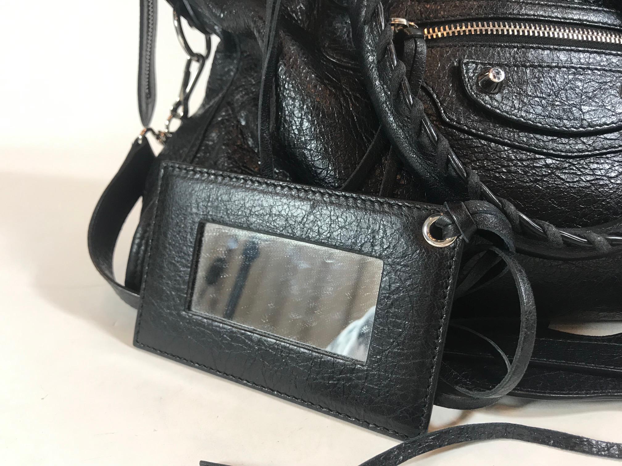 Black Arena leather. Silver-tone hardware. Two-way zip closures at top. Adjustable flat shoulder strap. Dual rolled handles featuring whipstitch trim. Exterior zip pocket at front. Raised stud embellishments featuring buckle adornments at exterior.