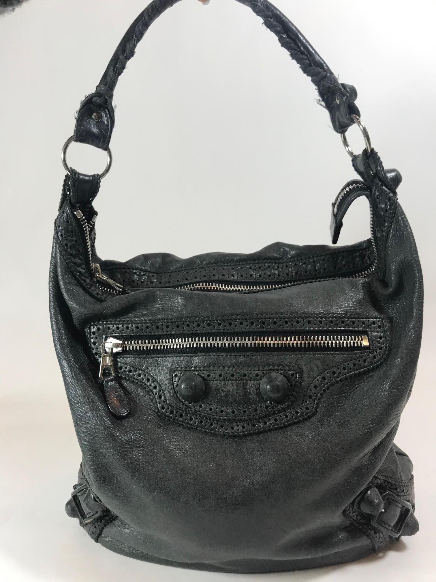 Black Arena leather. Silver-tone hardware. Zip closure at top. Single rolled top handle with metal ring accents and whipstitch detail. Single exterior zippered pocket at front. Featuring covered Giant stud accents. Perforated leather trim. Black
