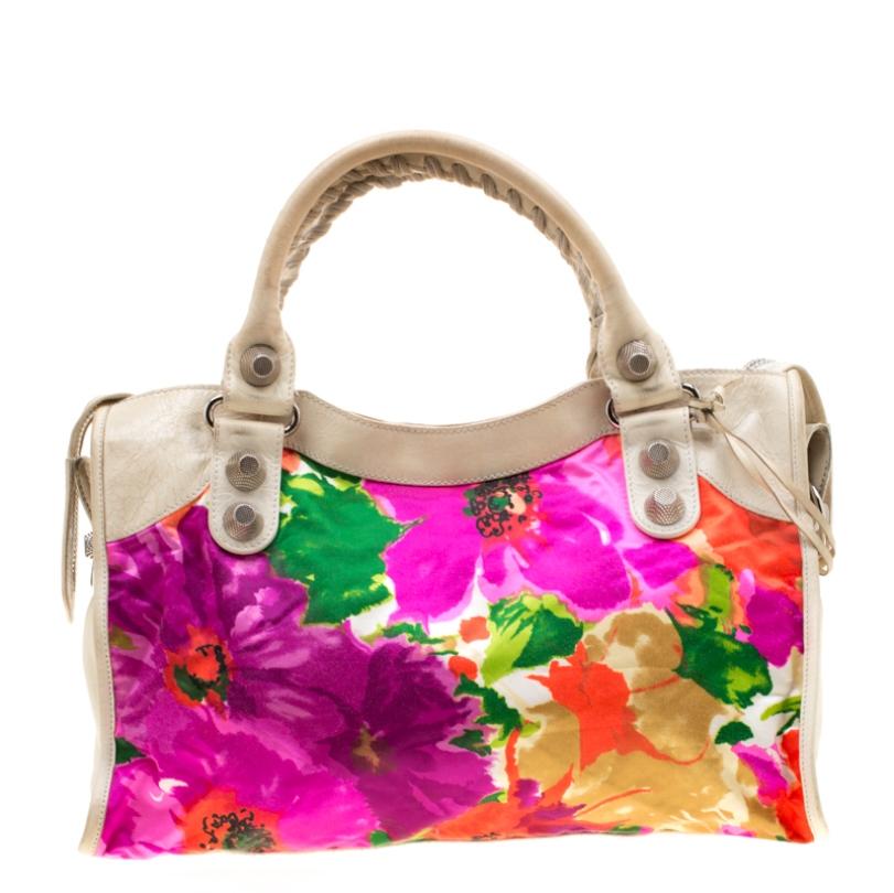 This dressy multicolor leather and satin piece is unique in its silhouette and features an interplay of large studs and buckles. With a creative floral print, the GSH City tote has a front zip pocket, round leather handles, and a removable shoulder